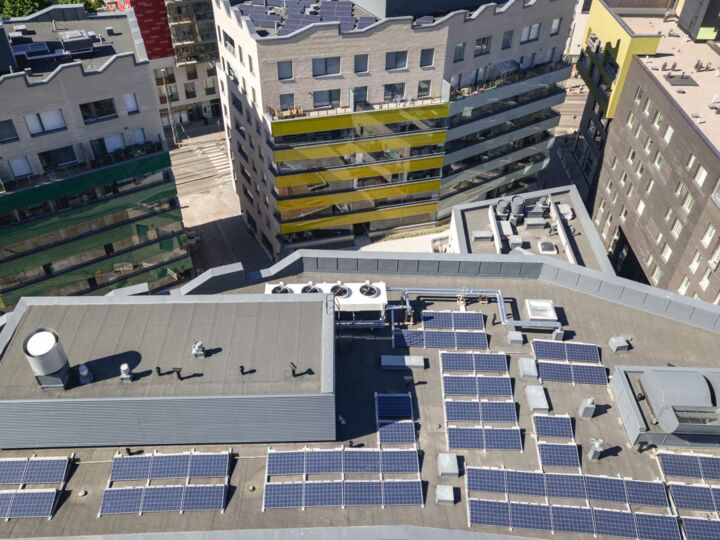 Aufsicht auf mehrere Däche mit Solarmodulen in einer dicht bebauten Stadt.