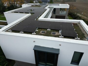 Auf dem Flachdach eines Wohnhauses sind einige Solarmodule installiert