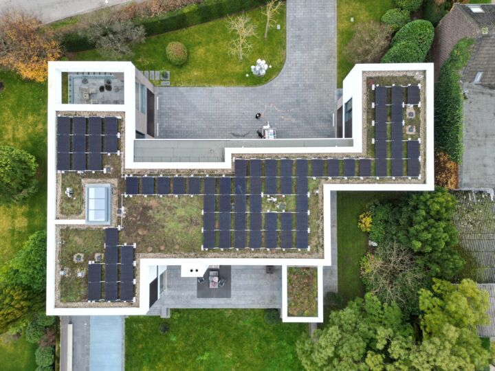 Blick aus der Vogelperspektive auf das Flachdach eines Mehrfamilienhauses. Fast die gesamte Dachfläche ist mit Solarmodulen belegt.