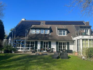 Auf dem Schrägdach einer Villa werden Solarmodule installiert